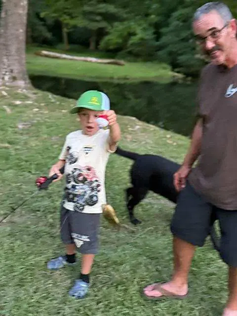 A young guest holding up a fish caught from the bank