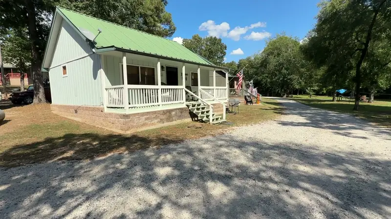 A cabin porch with white railings and a green metal roof