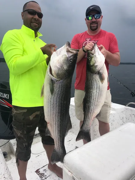 Two anglers holding striped bass caught on the lake